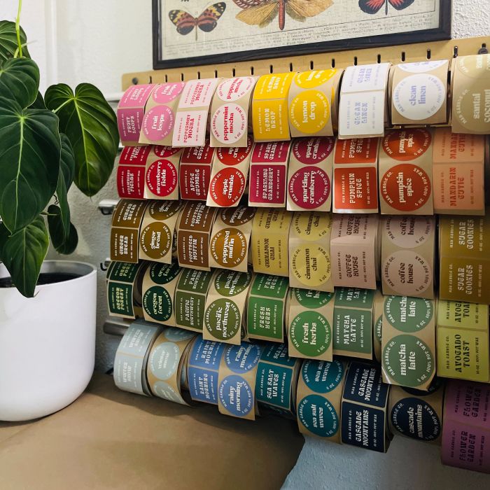A display wall filled with organized rolls of white Avery labels used for Mad Candle Co. candles.