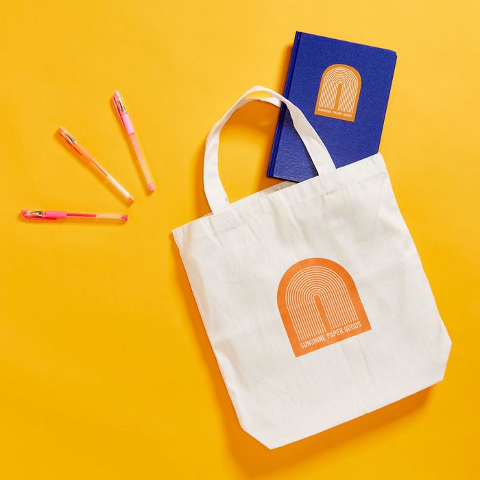 give a custom tote bag, journal and pins to the client on the go