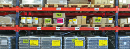 warehouse shelves stocked with inventory in various boxes and on palettes 
