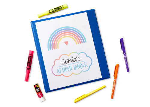 Flatlay of blue binder with cover reading, 'Camila's At Home Binder' with highlighters, a glue stick and permenent markers surrounding it.