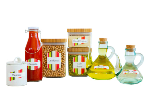 a row of neatly and colorfully labeled kitchen staples, like mustard, bread crumbs, and olive oil in glass and ceramic containers