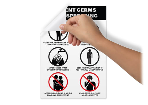 Surface Safe sign, featuring a black and red design with six tips on how to prevent the spread of germs and bacteria, on a blank wall being peeled off from the top lefthand corner by a person's hand.