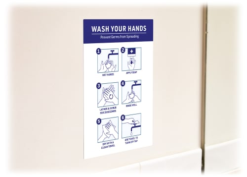 Angled view of a Surface Safe sign, featuring a blue design with six steps on how to properly wash your hands, on a blank tan wall.