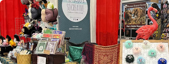 A shot of a vendor booth at a convention showcasing handcrafted headwear and accessories.