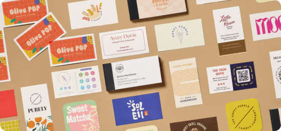 A flatlay of more than 20 different business cards and business card books of different shapes and design styles, sitting on a brown background. .