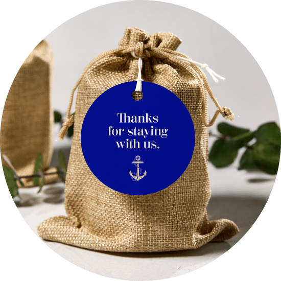 A deep blue Avery round tag with a beachside hotel design, tied around a burlap bag.