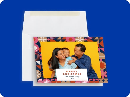 Two busness cards, one showing the front of the design with red text on a white background, and one showing the back of the design with a red background and a smiley-face logo that says 'Be Goods.' The cards are held and fanned out by their corners by a hand, against a deep blue background.