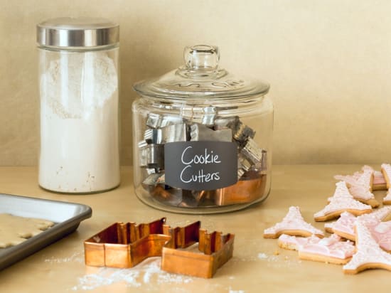 Display similar items, such as clunky cookie cutters, using apothecary jars and chalkboard labels.
