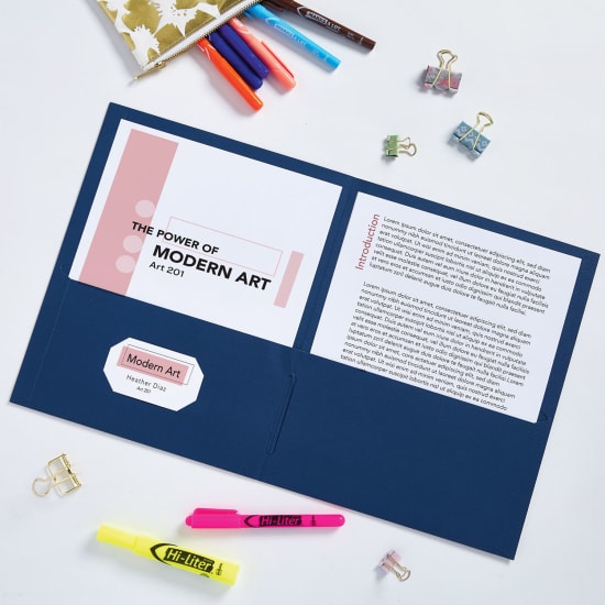 Flatlay image of a dark blue folder opened up and showcasing a report in its pockets with a business card in the card slot. It is surrounded by a yellow highlighter and a pink highlighter, as well as alligator clips, and a pencil case with colorful Avery fine tip permanent markers spilling out of it