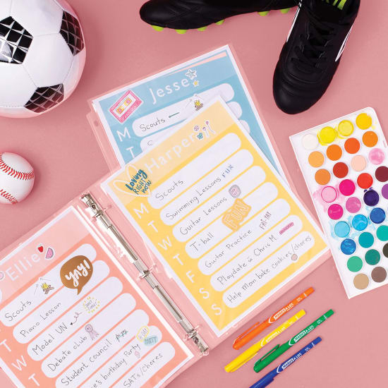 Flatlay image of Avery Clear Sheet Protectors that have been filled with colorful schedule sheets. They are surrounded by a soccer ball, a pair of cleats, a baseball, a watercolor paint palette, and colorful Avery fine tip markers, and everything is sitting on a rosy pink background
