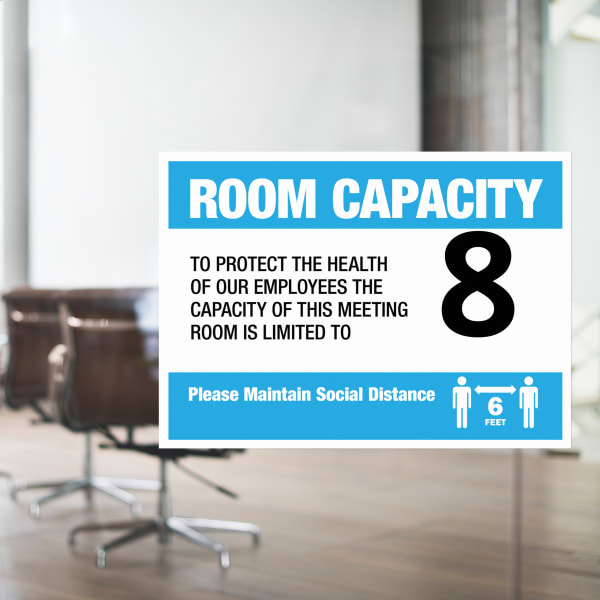 An adhesive sign that communicates the room capacity is adhered on a glass wall of an office meeting room. 