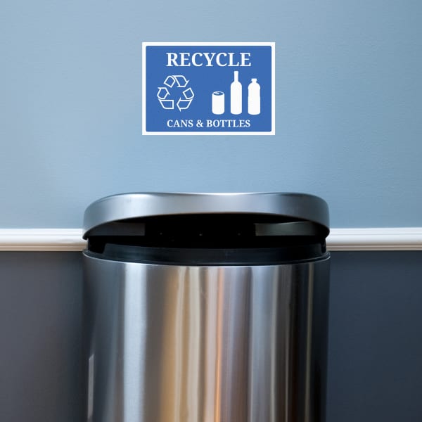 An adhesive sign for recycling posted on a painted wall above a trash can. 