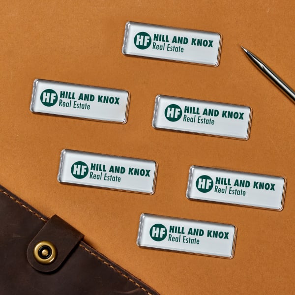 Professional magnetic name tags for work laid out on a desktop. The design features a company logo, the company name, and a simple tagline. 
