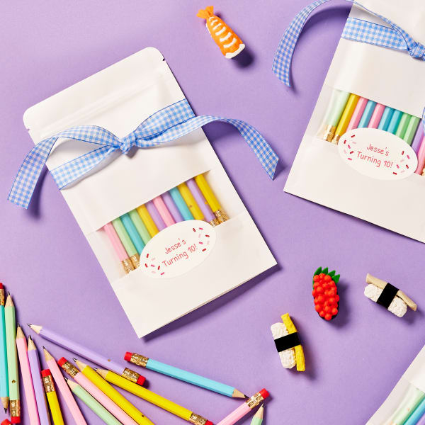 Colorful pencils are packaged together in a bag with a cute blue-gingham ribbon and sprinkle-themed personalized label. 