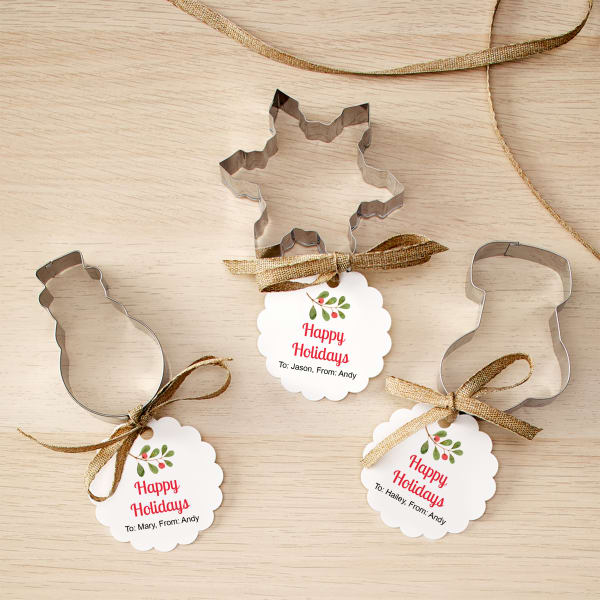 Personalized tag for cookie cutters are printed on Avery 80511 scalloped round label. Each tag has a holly branch and the words "Happy Holidays" and then is personalized with individual "To/From" messages.
