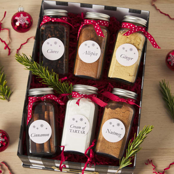 Spice jar Christmas gift idea for coworkers shows a gift box of spices labeled with Avery round label 22807. The labels are simple with elegant snowflakes and the name of each spice. 