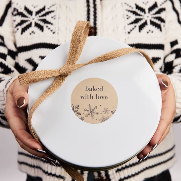 "Baked with Love" label for baked gifts is printed on Avery round Kraft label 22818. It is shown on a round cookie tin. 