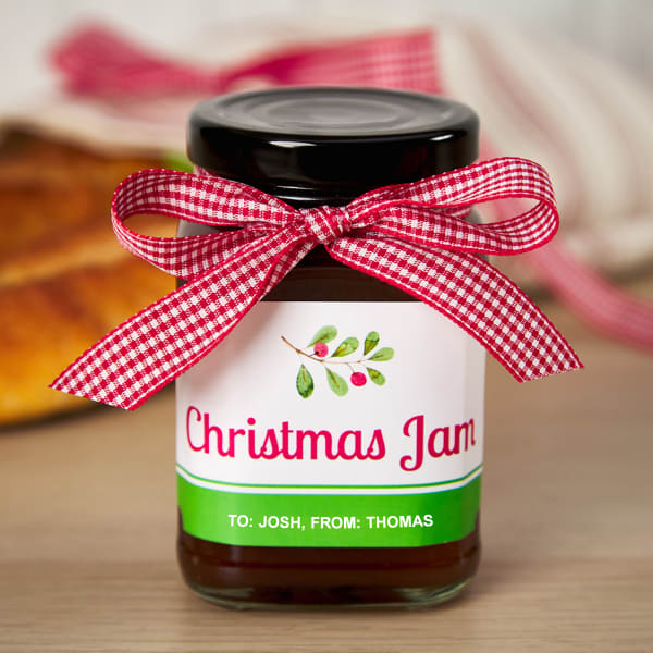 Personalized jam labels for Christmas gifts printed on Avery 2 inch by 4 inch blank labels by the sheet. The label is red and green with a holly branch and reads, "Christmas Jam."