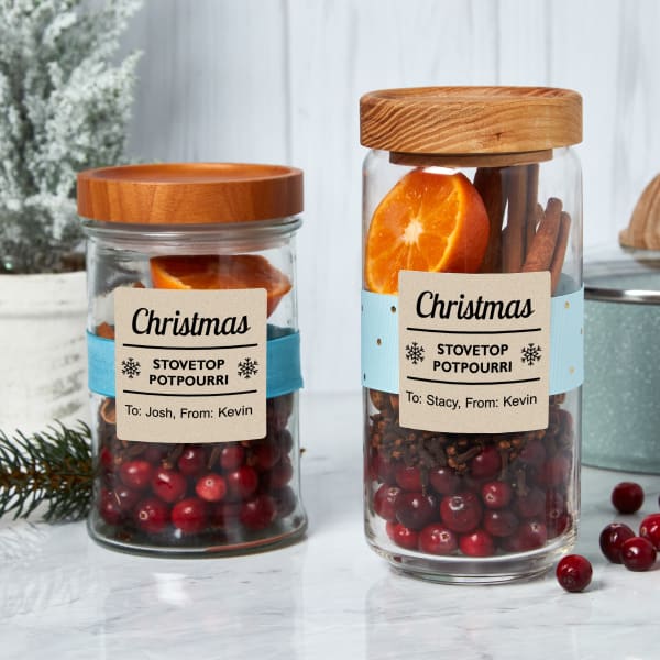 Stovetop potpourri Christmas party favors are demonstrated with jars filled with cranberries, orange slices and cinnamon sticks. The jars are decorated with square Avery Kraft paper labels 22846. 