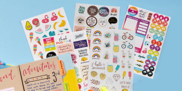 Colorful Avery planner stickers fanned out next to an open planner.
