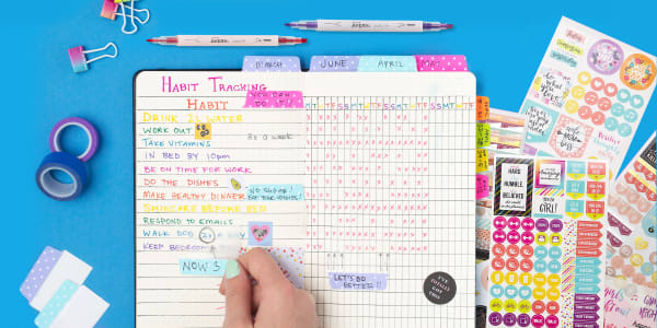 Image showing a color-coded planner on a blue surface surrounded by different colored planner accessories and colorful planner stickers