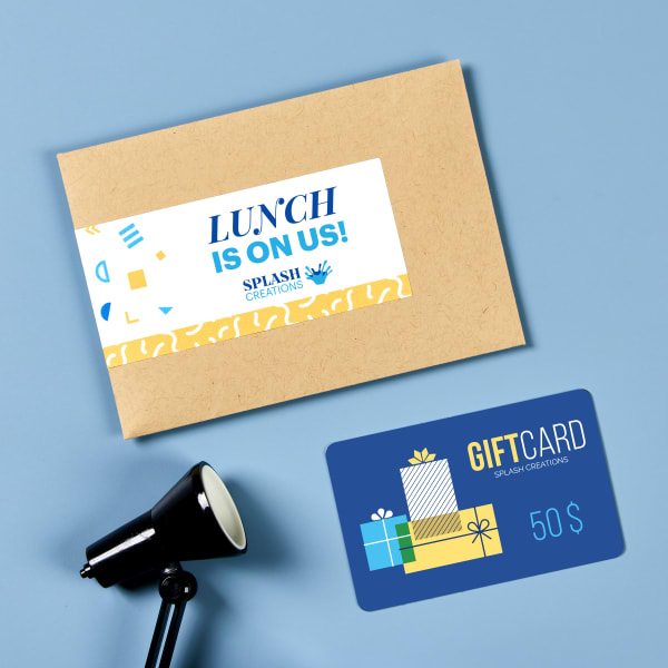 An envelope and gift card on a blue table. The envelope has been personalized with Avery label 22838 and reads, " Lunch is on us!"