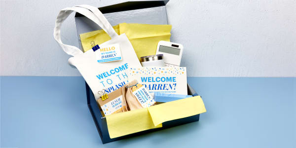 An onboarding kit shown assembled in a box with tissue paper. The items are personalized with Avery labels, cards, tags, and fabric transfer 3271.