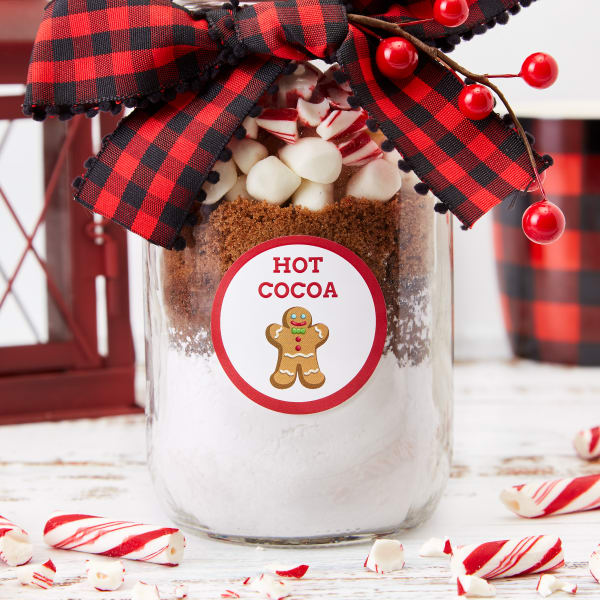 Hot cocoa idea for Mason jar gift showing layers of white and classic hot chocolate mix, marshmallows, and crushed candy canes. The jar is decorated with a bow and an Avery 22807 label.