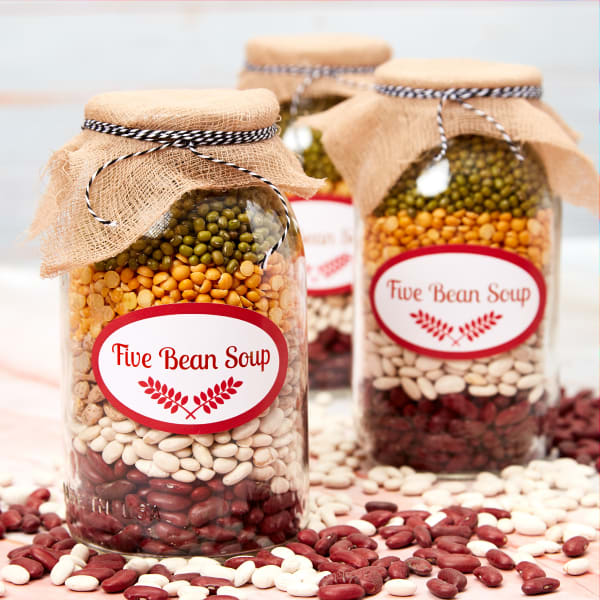 An example of a soup-in-a-jar gift with recipe. The image shows three jars layered with beans and ingredients for a hardy winter soup. The jars are decorated with burlap, string, and Avery 22820 oval labels.
