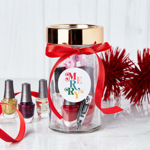 "Merry" mani-pedi Mason jar gift idea showing how to put together nail supplies to make a cute gift in a jar. The jar is topped with a red ribbon and an Avery 22807 label printed with a colorful design that reads, "Merry."