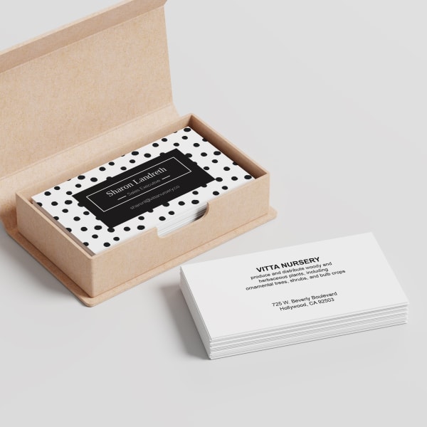 Modern dots in graphic black and white stand out on this business card template. A stack of Avery 28878 business cards showing the front of the card are neatly stacked in a Kraft card box and a second stack showing the back are stacked on the table next to it. 