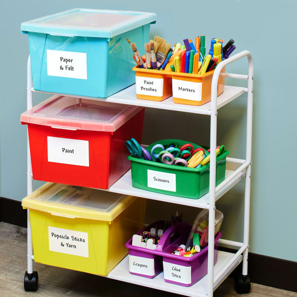 Colorful plastic bins, labeled with Surface Safe ID labels, sitting on an office trolley filled with arts & crafts supplies.