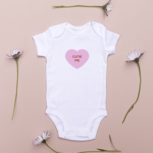 Image showing white baby onesie with made with an Avery Valentine’s Day template of a pink heart that reads “cutie pie.”