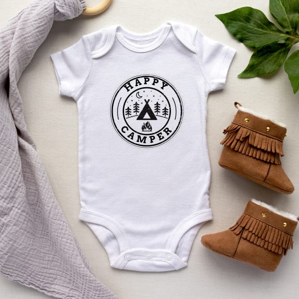 Image showing white baby snapsuit  with a cute campsite graphic and font that reads “happy camper.”