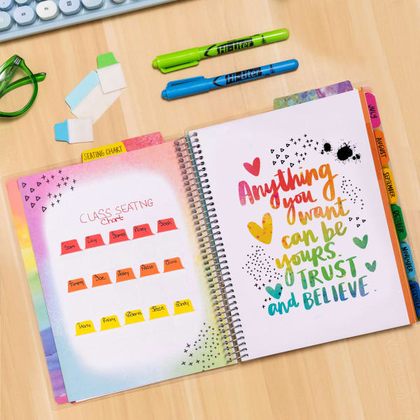 Avery and  Amy Tangerine teacher planner 29879 is shown open to a divider page with an inspirational quote that reads, "Anything you want can be yours. Trust and believe." The opposite side of the planner is used to create a class seating chart with Avery Ultra Tabs 74762. 