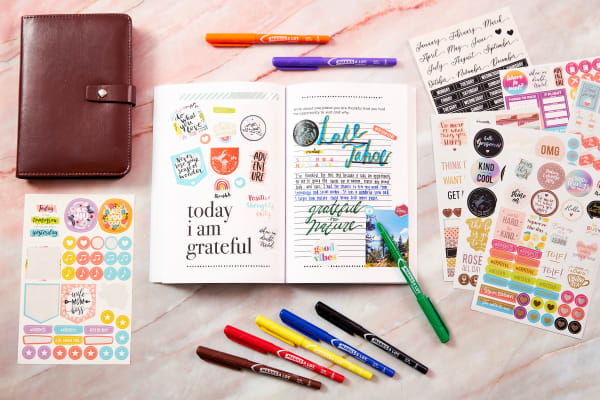 A beautifully decorated journal with planner stickers, markers and a leather journal cover