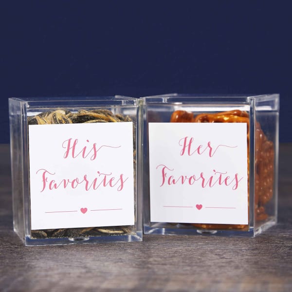 Wedding party favor examples of "His & Hers" favorite snacks. Clear boxes are filled with snacks and each box is labeled with Avery 22806 square labels that read either, "His Favorites," or "Her Favorites."