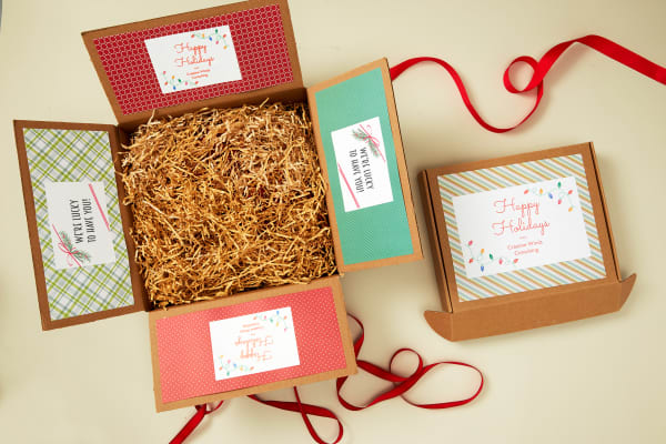 birds eye view of a regular shipping box decorated with festive labels for a holiday care package box and holiday shipping labels for mailer boxes made with avery templates and avery shipping labels with trueblock