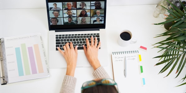 top down view of a person on a video conference call while working from home they have relevant reports neatly organized in an avery binder and a note pad with avery ulratabs used to organize and book mark notes while they are typing in the zoom chat with colleaguesr