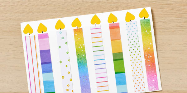 example of a birthday card kids craft made with avery labels and blank greeting cards and colorful printed paper cut out to look like birthday candles shown close up on a light wood table