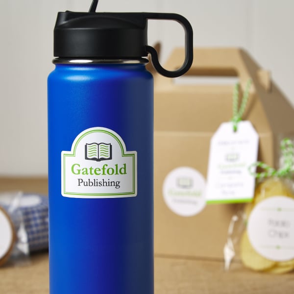 Close up of a bright blue reusable metal water bottle with a company logo decal on it. In the background are branded picnic lunch items. 