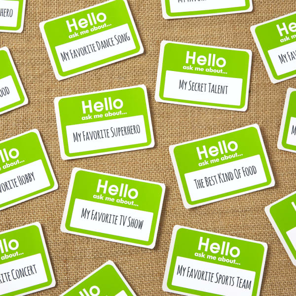 Avery printable name badges 8395 printed with icebreakers to use for company picnic activities. The name badges each feature a green border that reads, "Hello, ask me about..." and then a different idea. For example, my favorite TV show, my secret talent, my favorite dance song and similar things. 
