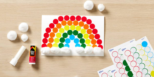showing the final step of how to make a rainbow greeting card using color coding labels and cotton balls on a blank avery greeting card