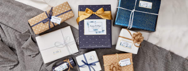 gray and white cloth surface with holiday wrapped gift boxes topped with matching custom avery labels tags and cards