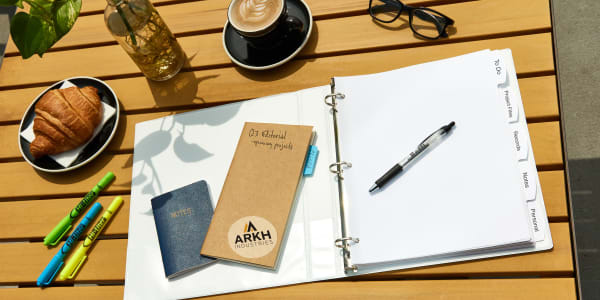 Outdoor wooden coffee shop table  with an open durable Avery binder showing Avery dividers used as a portable filing system.