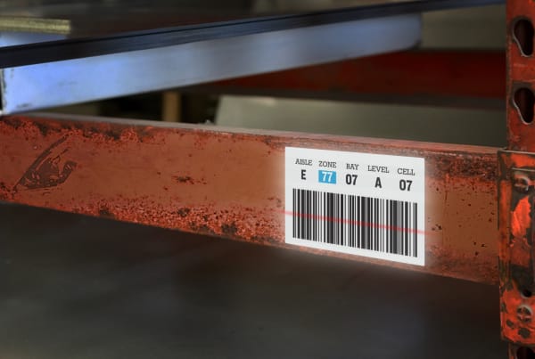bright white asset tag with barcode on industrial facility inventory shelf