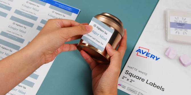 Image of a person applying a custom printed square black out label to a metal tea tin, with Avery label sheets and packaging for square labels visible in the background.