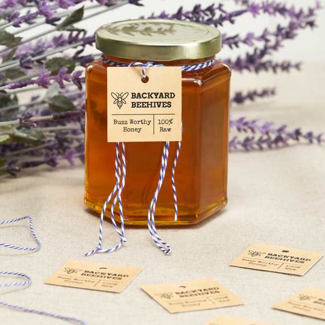 Image showing a jar of honey packaged for a farmers market. Tied around the jar is a custom kraft paper Avery tag with the company name and bee logo.