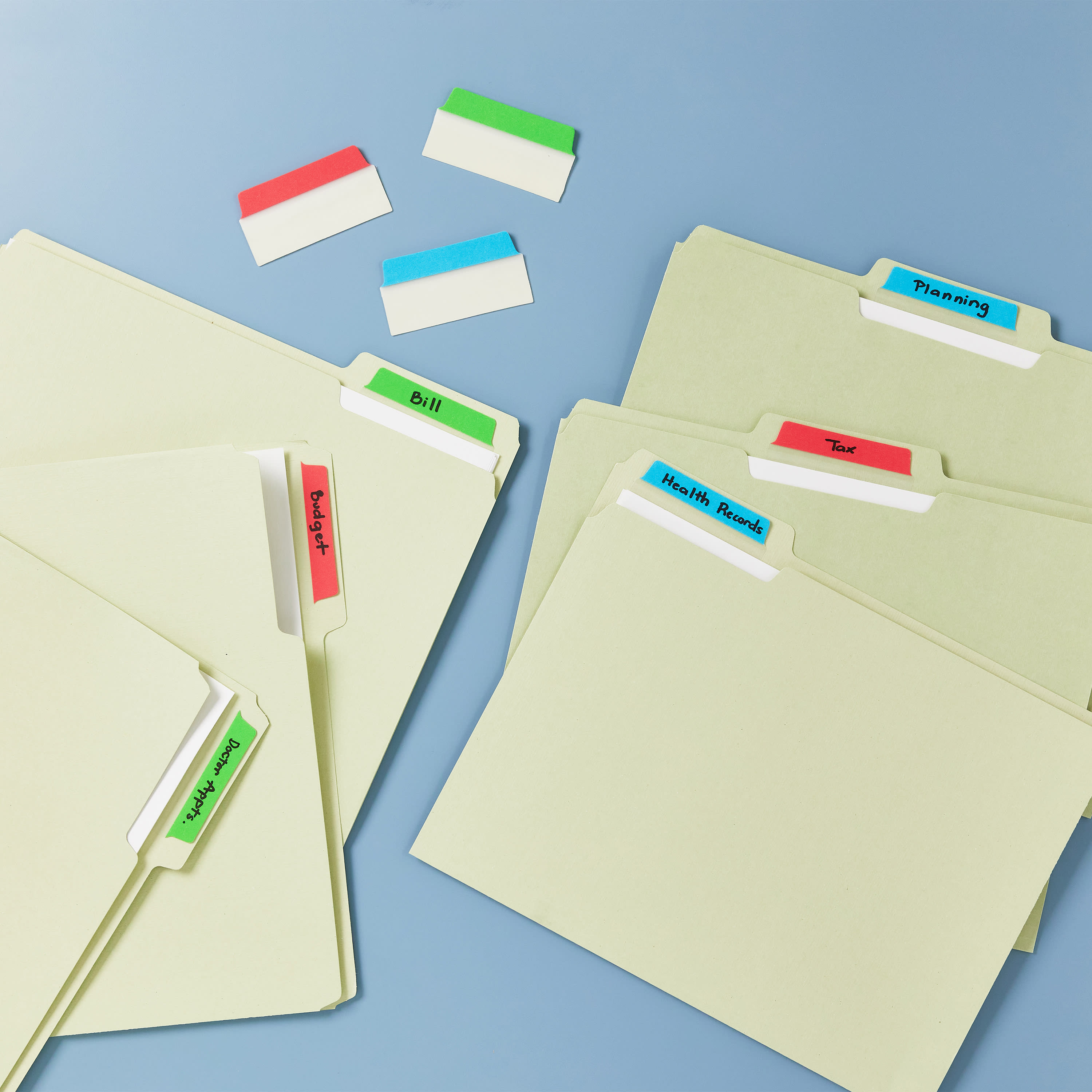 Loose file folders are fanned out on a desk. Avery UltraTabs 74775 are are used to label the file folders instead of labels. Things like, "Health Records," "Budget," "Doctor Appts." etc. are hand written on the UltraTabs.
