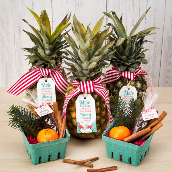 pineapples tied with festive gift tags next to other fruits